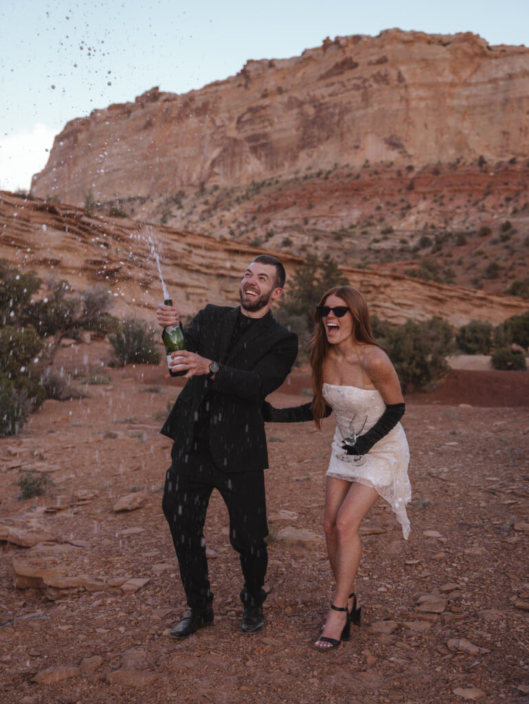 Spraying champagne - desert engagement shoot