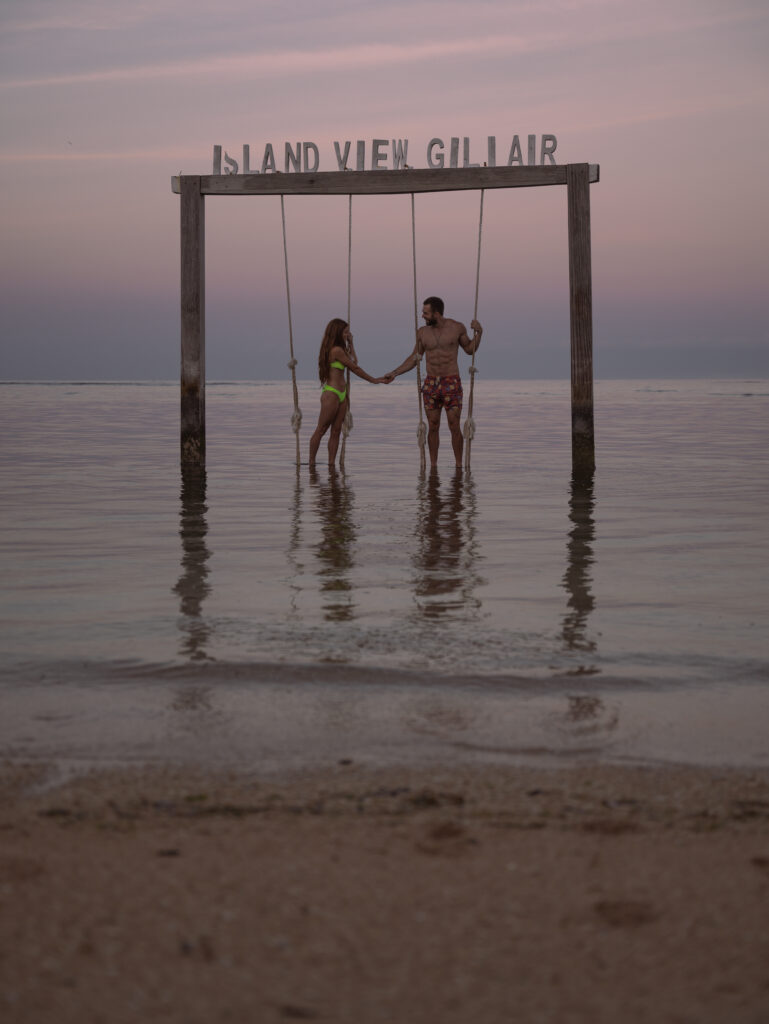 Lia & Matt on a swing set in the water at sunrise