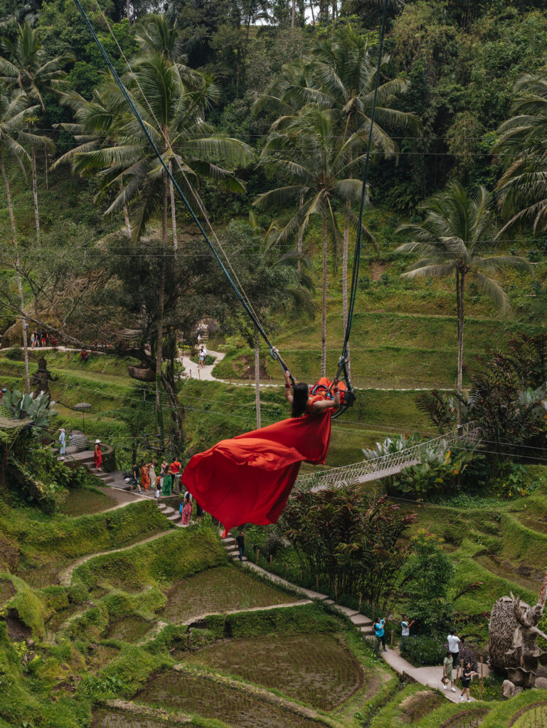 A girl in a red dress swinging over the rice terraces