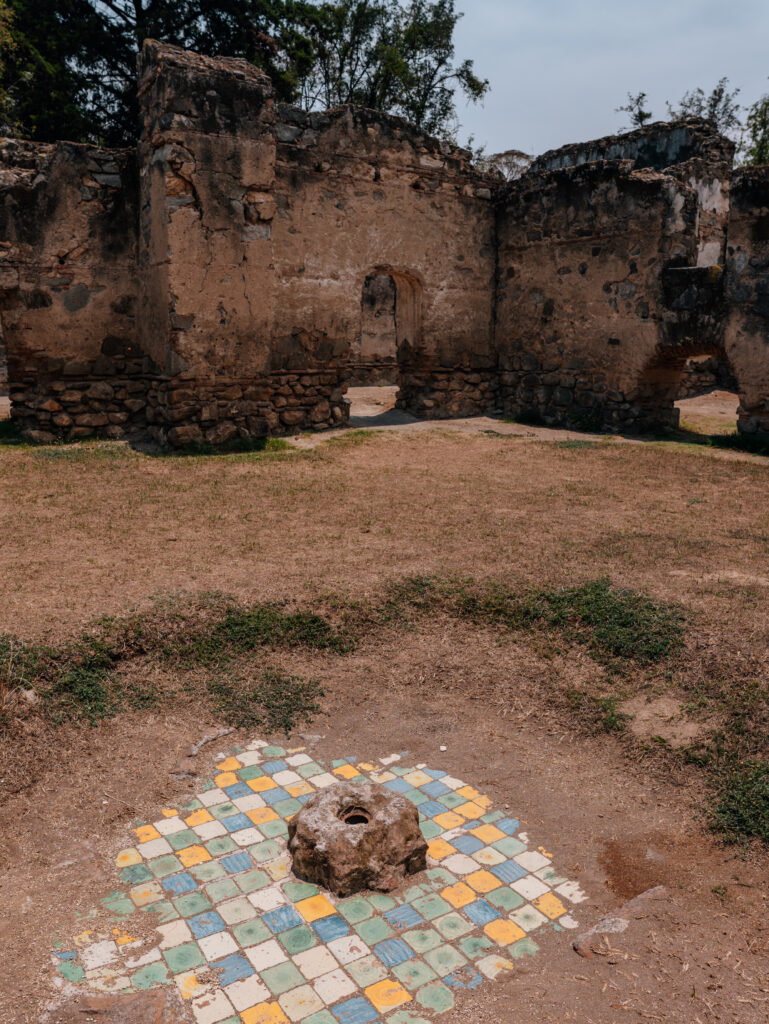 A courtyard with colorful tiles visible among the dirt